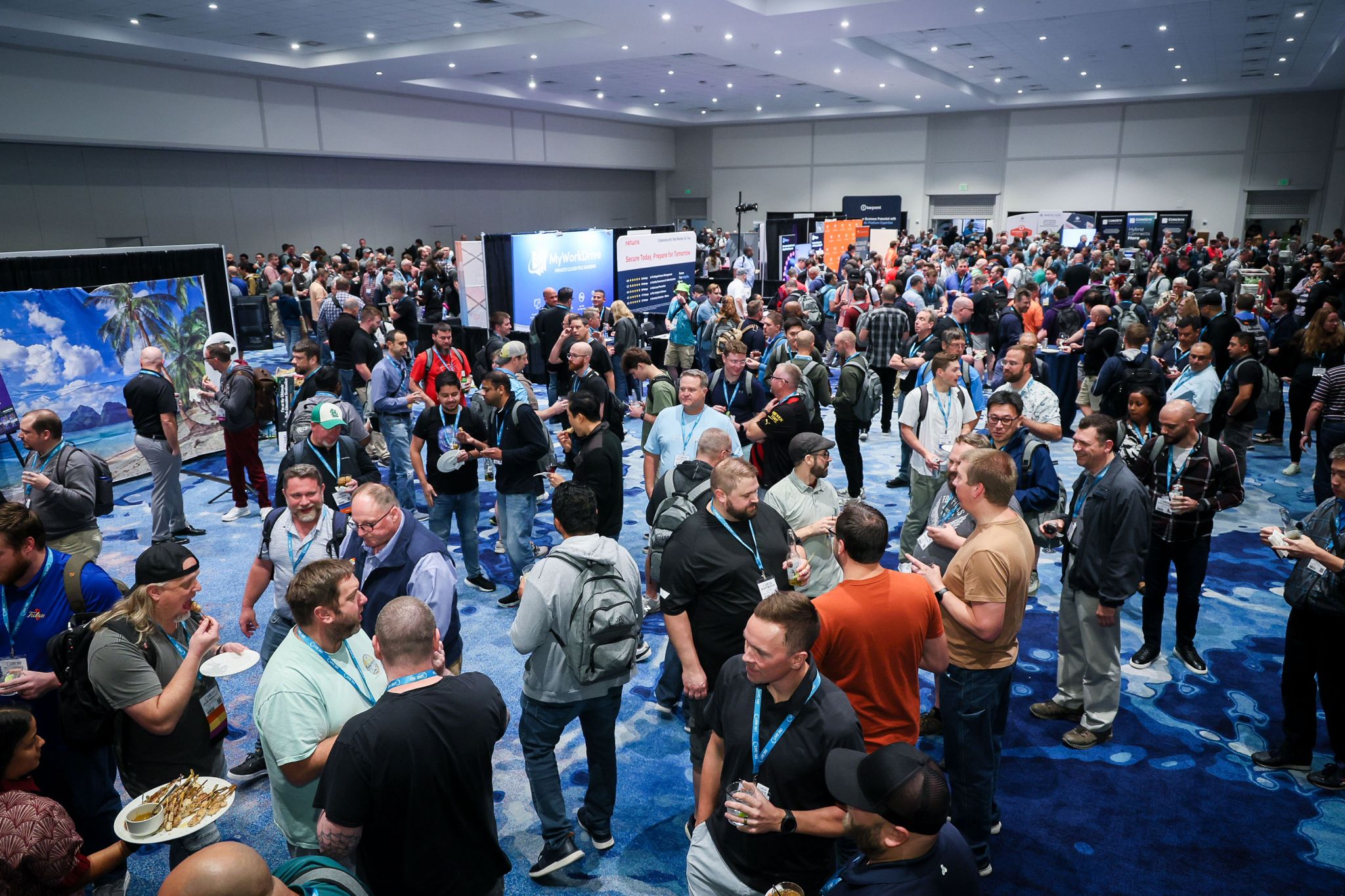 A crowded Live! 360 Welcome Reception in the EXPO hall, with attendees holding drinks and plates among sponsor booths.